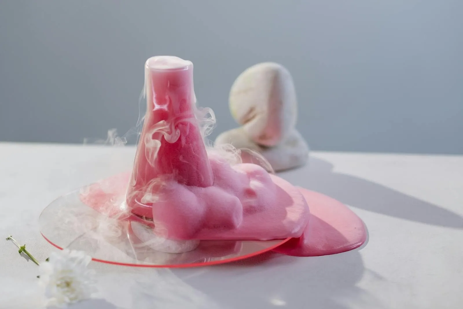 Vibrant pink foam overflowing from a flask in a clean, modern laboratory setting.