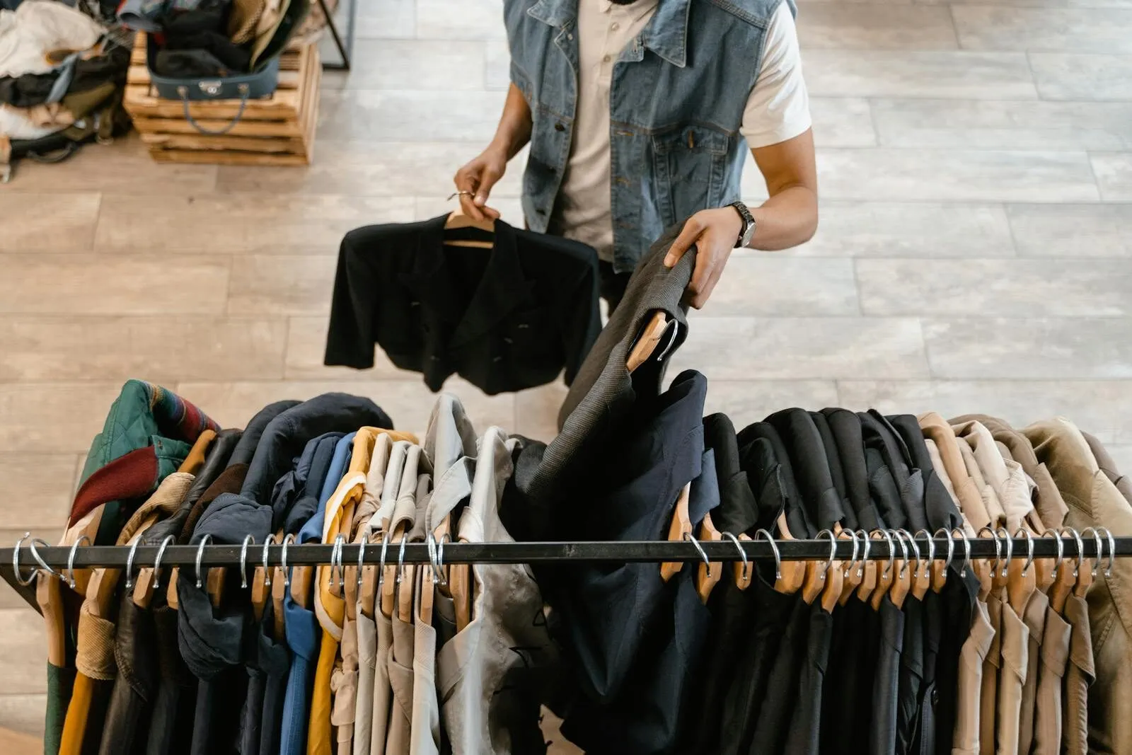 Person organizing secondhand fashion on a rack illustrating DPP resale and authenticated secondhand clothing