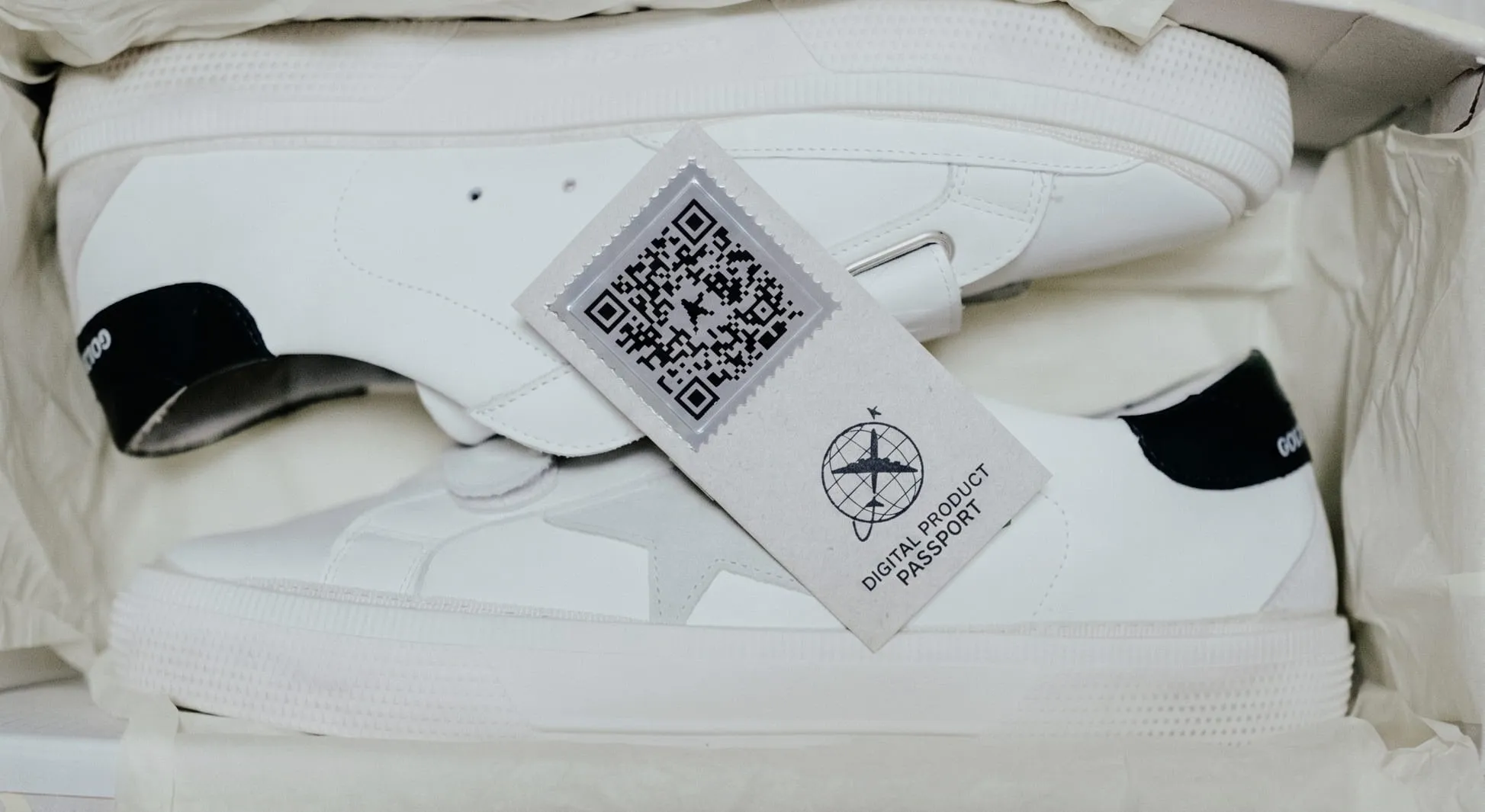 A pair of white sneakers in a box with a QR Code for Digital Product Passport