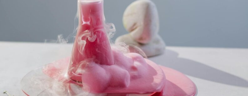 Vibrant pink foam overflowing from a flask in a clean, modern laboratory setting.