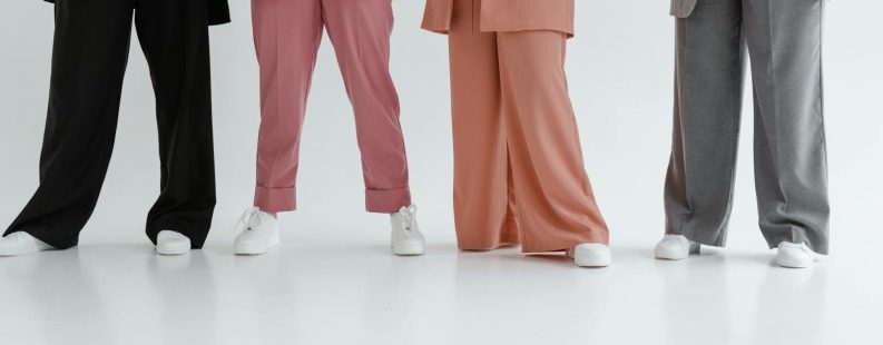 Fashionable women in stylish suits posing indoors on a white background.