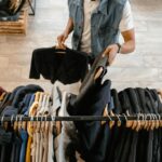 Person organizing secondhand fashion on a rack illustrating DPP resale and authenticated secondhand clothing