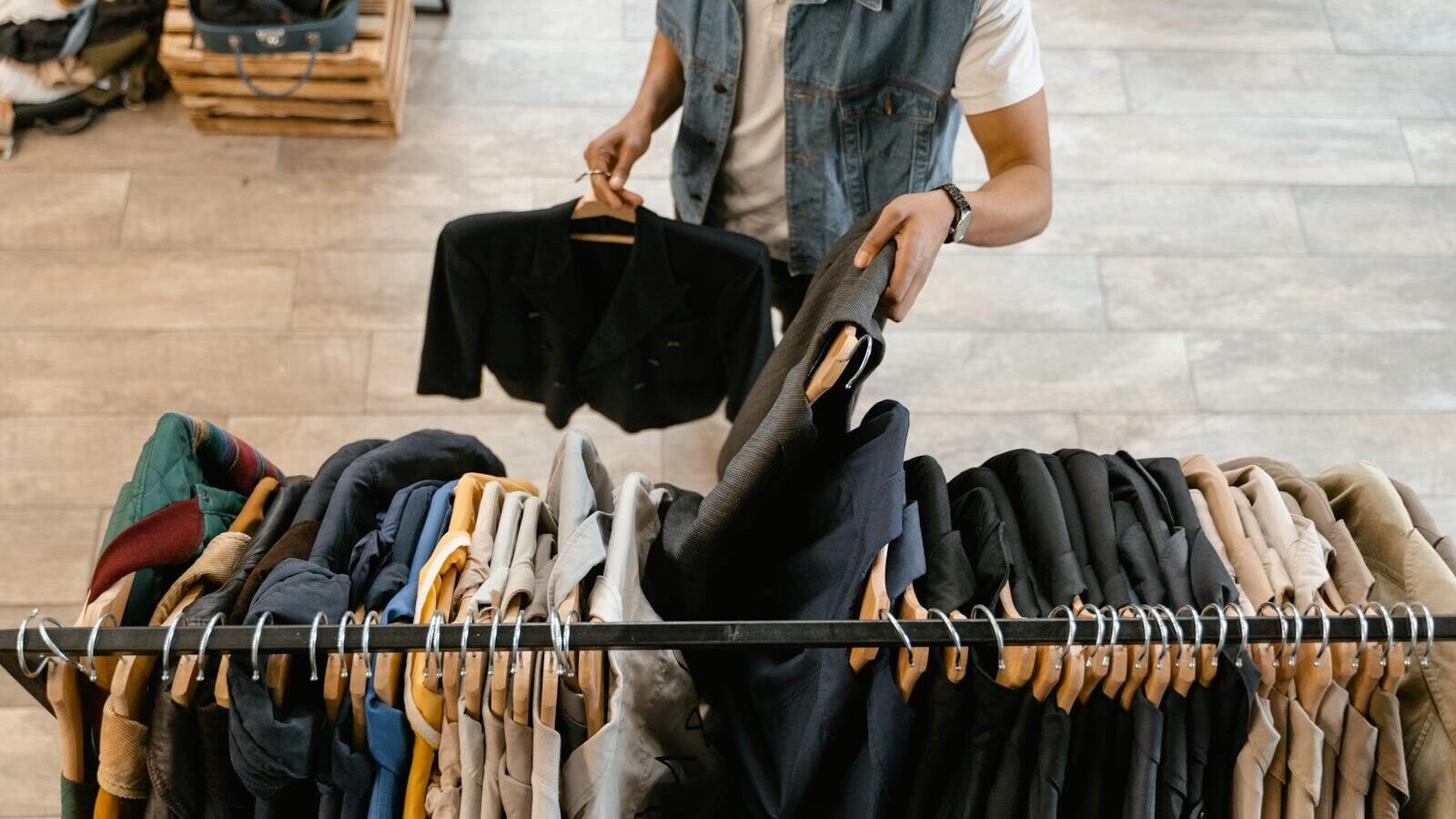 Person organizing secondhand fashion on a rack illustrating DPP resale and authenticated secondhand clothing