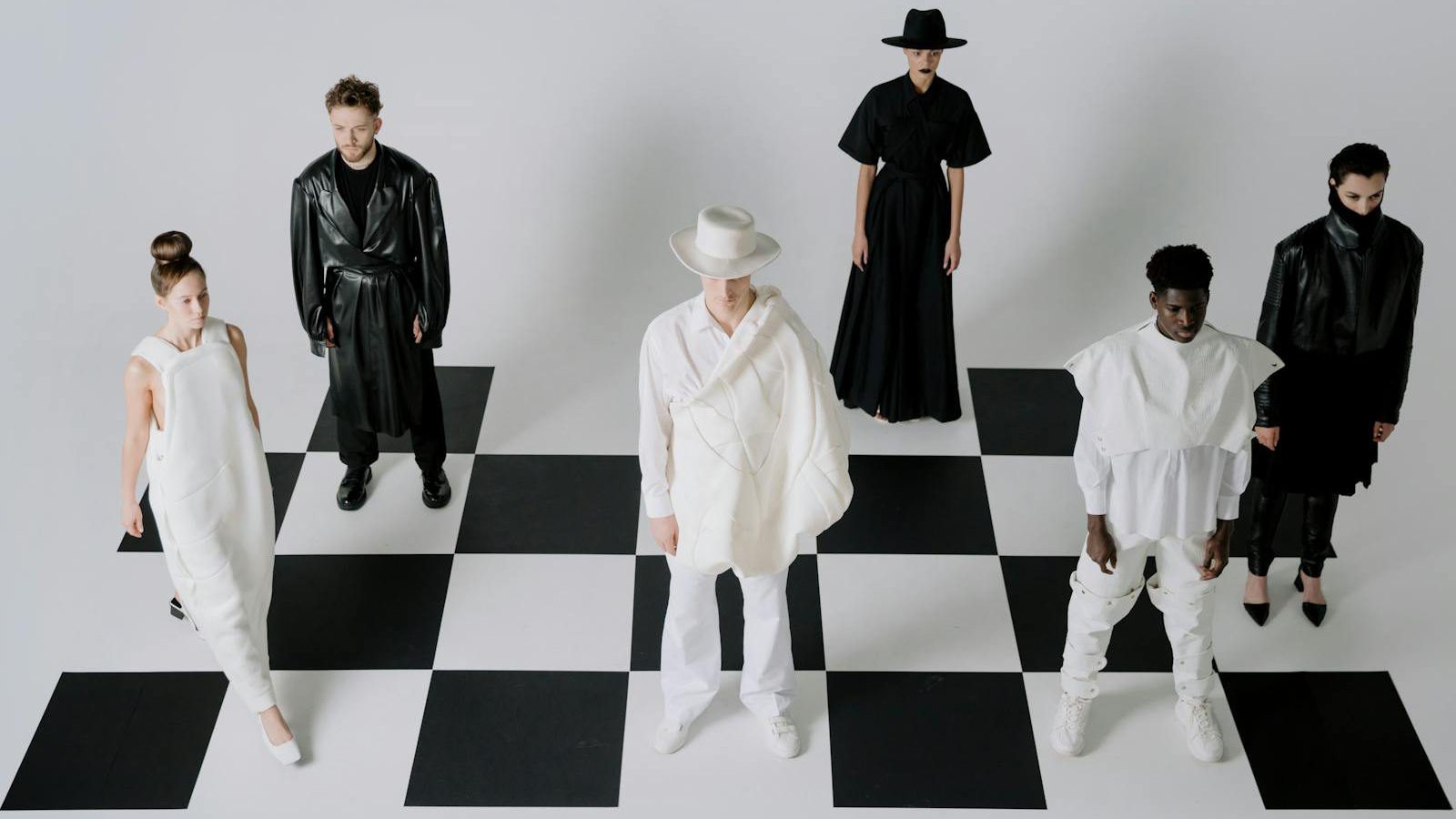 Stylish fashion models in black and white outfits on a chessboard backdrop.