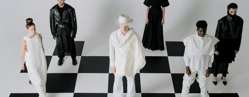 Stylish fashion models in black and white outfits on a chessboard backdrop.
